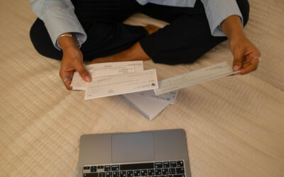 Woman holding three cheques in front of a laptop