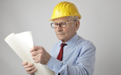Elderly man in hard hat and shirt and tie.