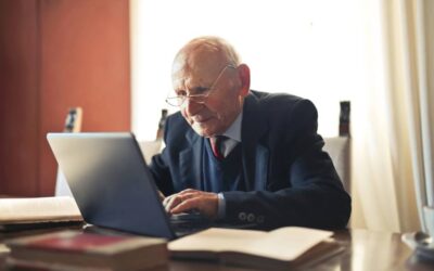 Elderly man in a suit working on a laptop