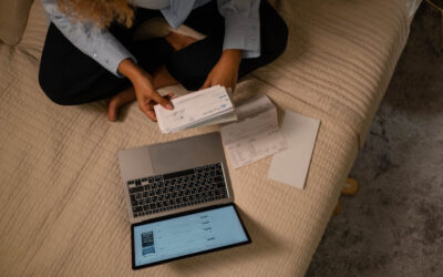 Person looking at a stack of cheques with a laptop