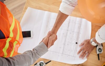 Two people shaking hands over JCT Contracts, one wearing white shirt, the other wearing a hi-vis vest