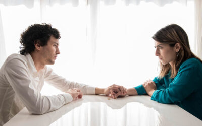 Couple looking at each other and holding hands on either side of table