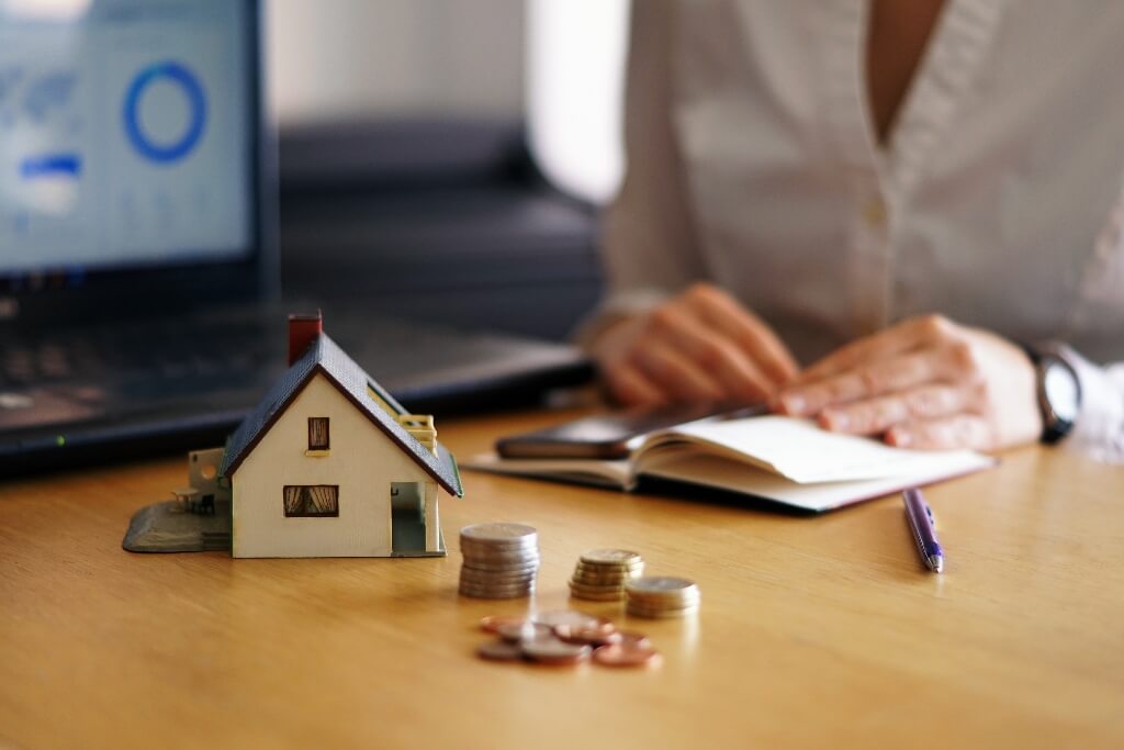 Woman working in a notepad next to a model of the house