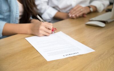 Woman signing a contract next to a man in a shirt