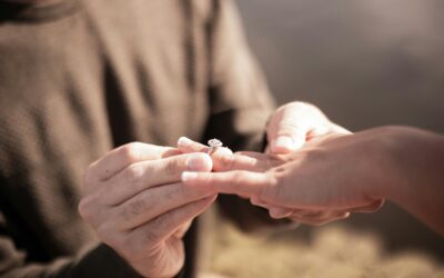 hands putting an engagement ring on another person's finger