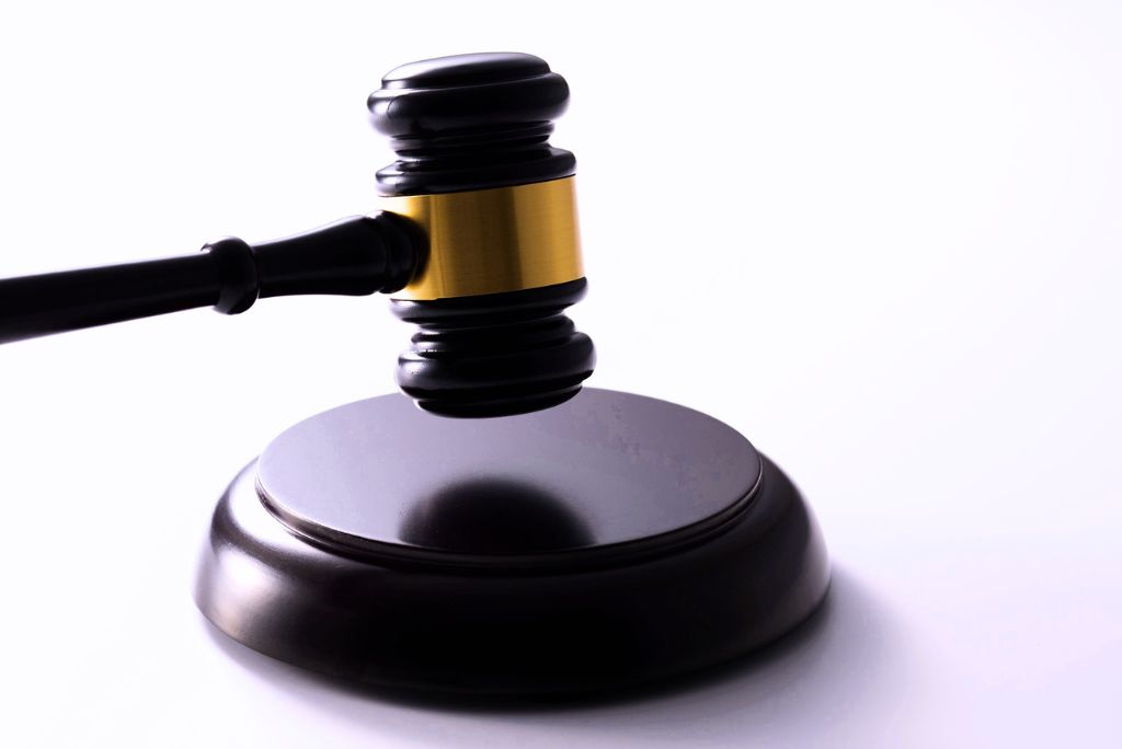 A judge’s gavel with a sound block against a plain background.