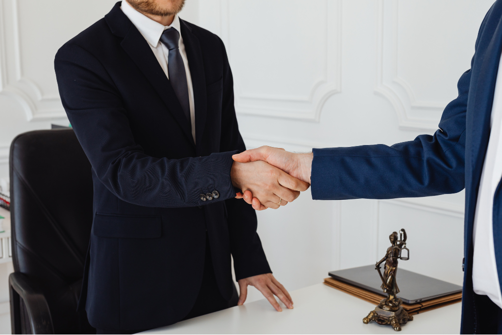 Two people in business suits shaking hands in a law firm office